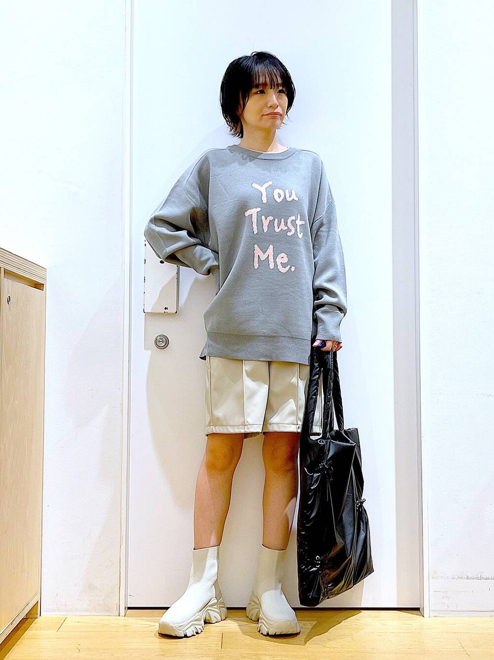 グレー系のニット/セーター、ブラック系のトートバッグ、ベージュ系のブーツを着用したレディースの冬コーディネートの1枚目の写真