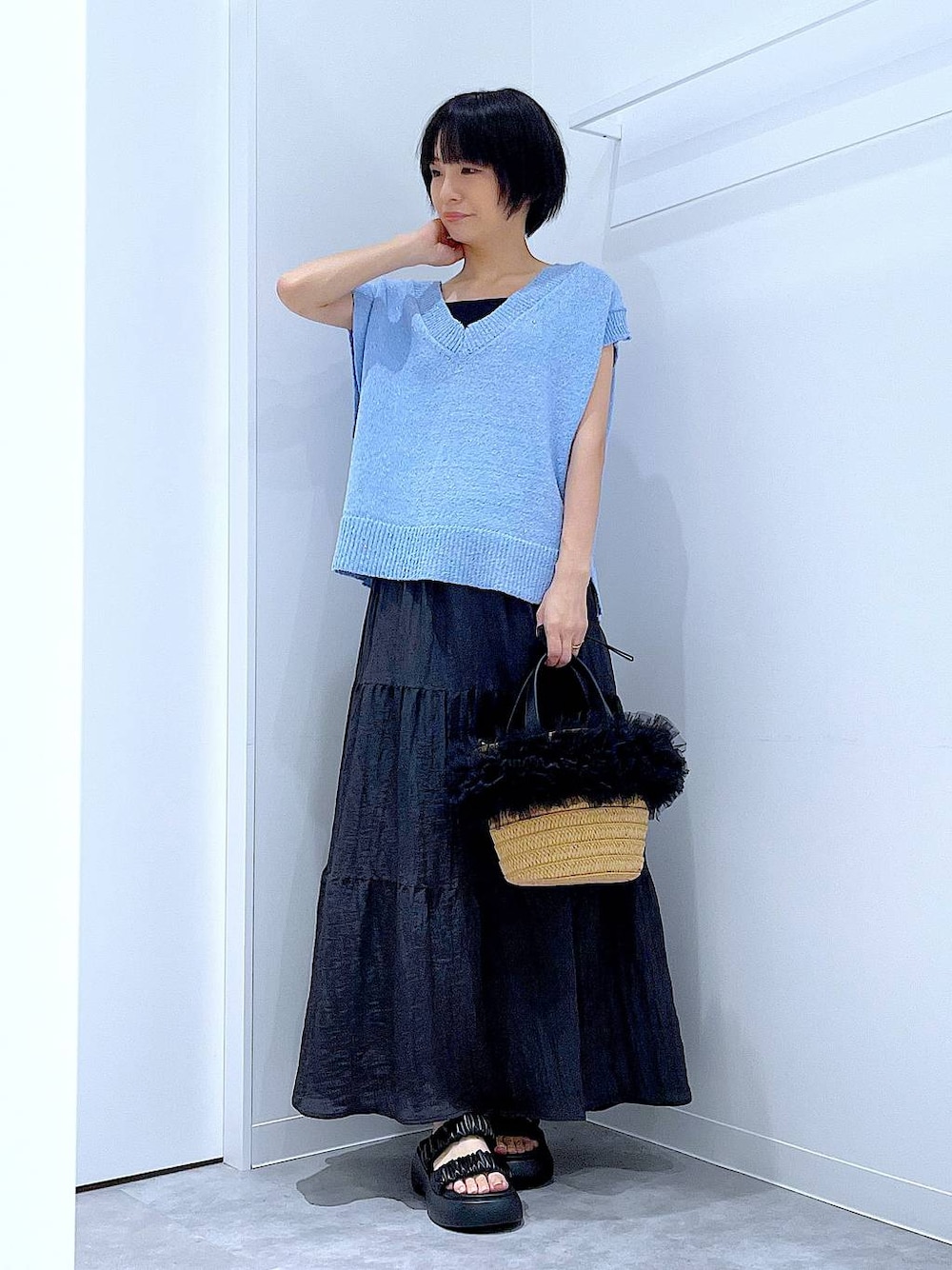 ベージュ系のショルダーバッグ、ブラック系のサンダル、ブルー系のベストを着用したレディースの夏コーディネートの1枚目の写真