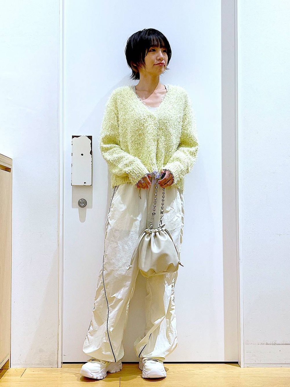 ベージュ系のショルダーバッグ、ホワイト系のスニーカー、イエロー系のカーディガン/ボレロを着用したレディースの秋コーディネートの1枚目の写真