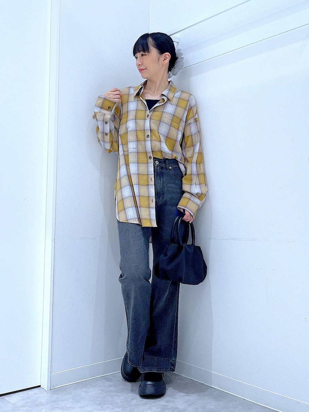 ブラック系のハンドバッグ、ブラック系のデニムパンツ、イエロー系のシャツ/ブラウスを着用したレディースの秋コーディネートの1枚目の写真