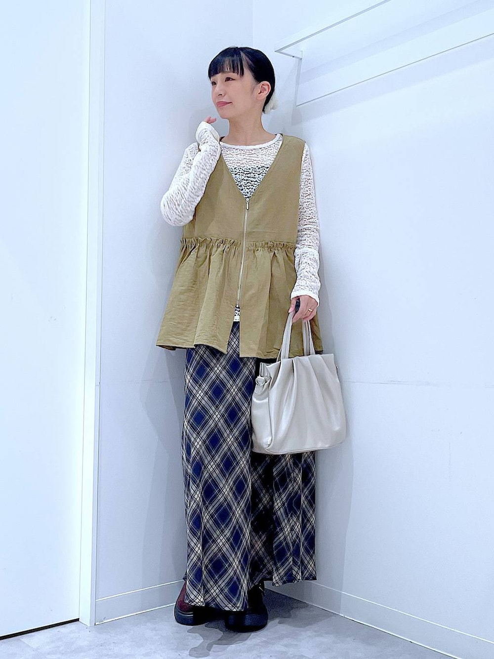 イエロー系のベスト、ホワイト系のTシャツ/カットソー、ホワイト系のハンドバッグを着用したレディースの夏コーディネートの1枚目の写真