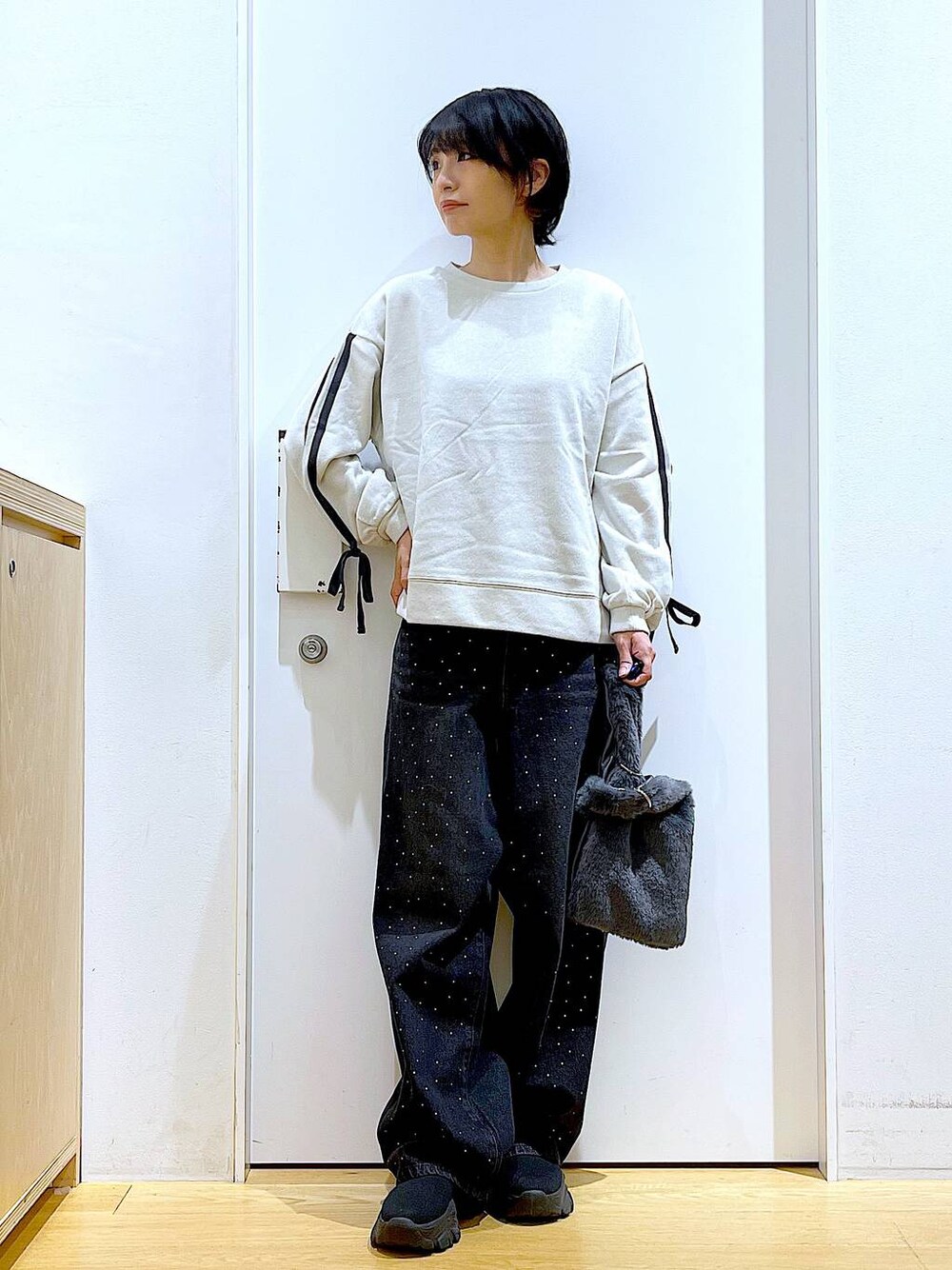 グレー系のショルダーバッグ、ブラック系のブーツ、ベージュ系のスウェットを着用したレディースの秋コーディネートの1枚目の写真