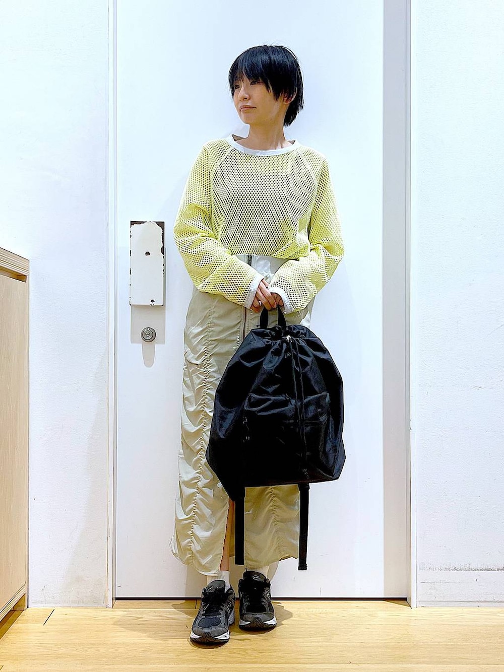 ベージュ系のスカート、ブラック系のバックパック/リュック、イエロー系のTシャツ/カットソーを着用したレディースの春コーディネートの1枚目の写真