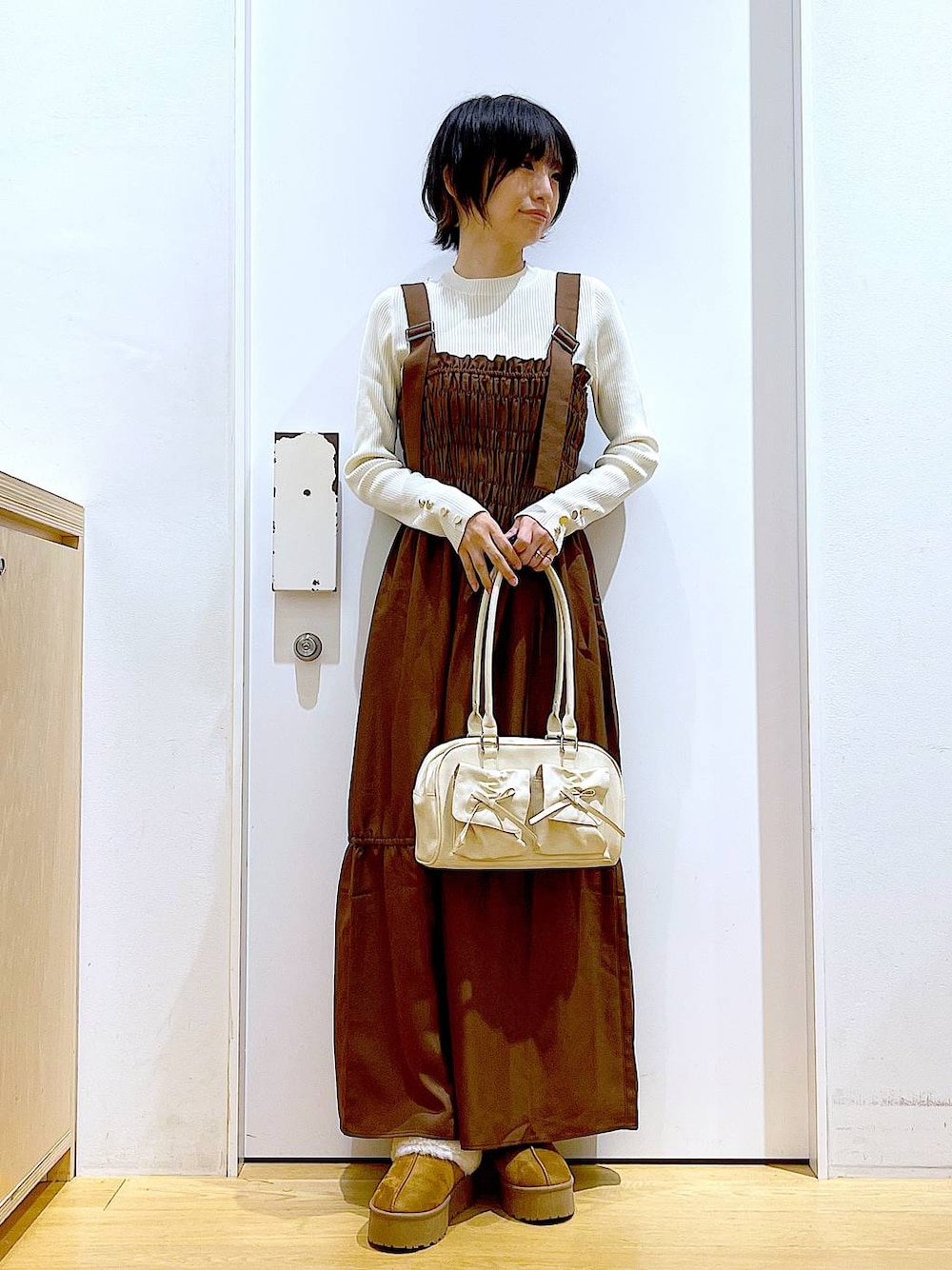 ホワイト系のニット/セーター、ホワイト系のハンドバッグ、ベージュ系のスリッポンを着用したレディースの冬コーディネートの1枚目の写真