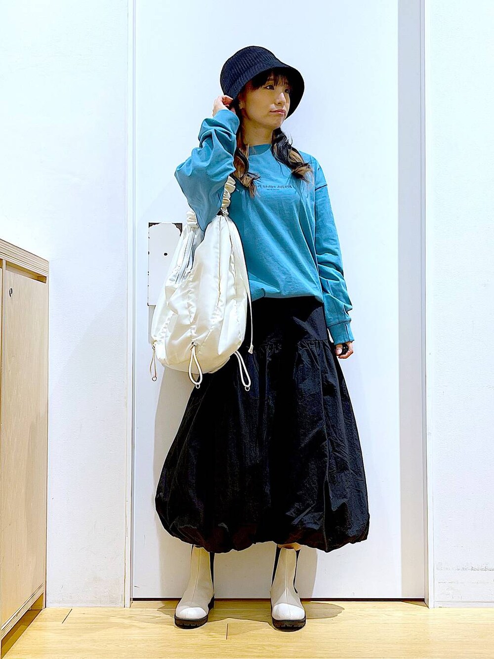 グリーン系のTシャツ/カットソー、ベージュ系のブーツ、ホワイト系のショルダーバッグを着用したレディースの春コーディネートの1枚目の写真