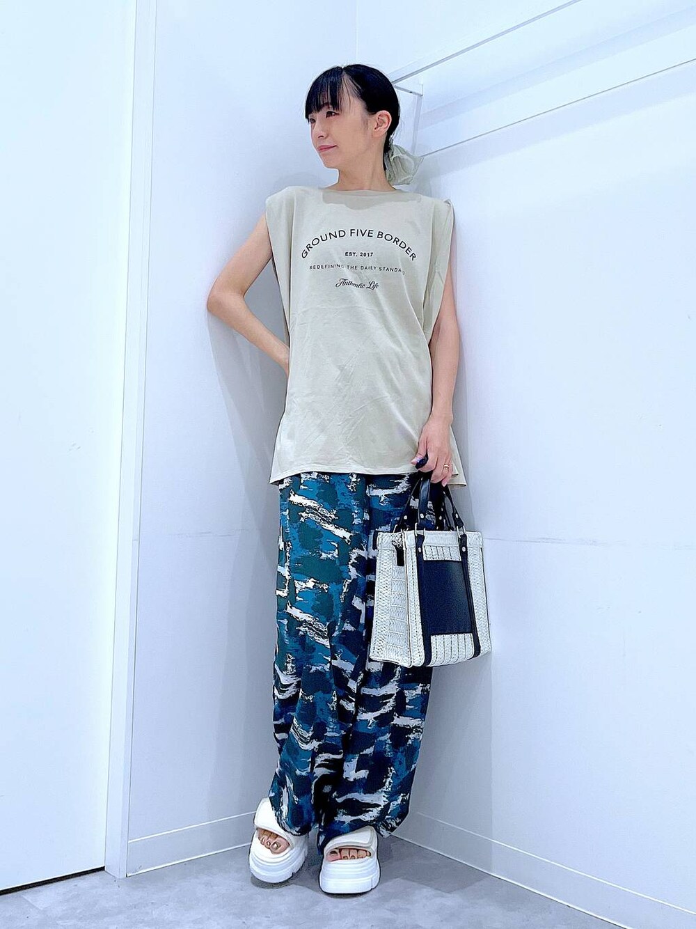 ホワイト系のショルダーバッグ、ホワイト系のサンダル、ベージュ系のTシャツ/カットソーを着用したレディースの夏コーディネートの1枚目の写真