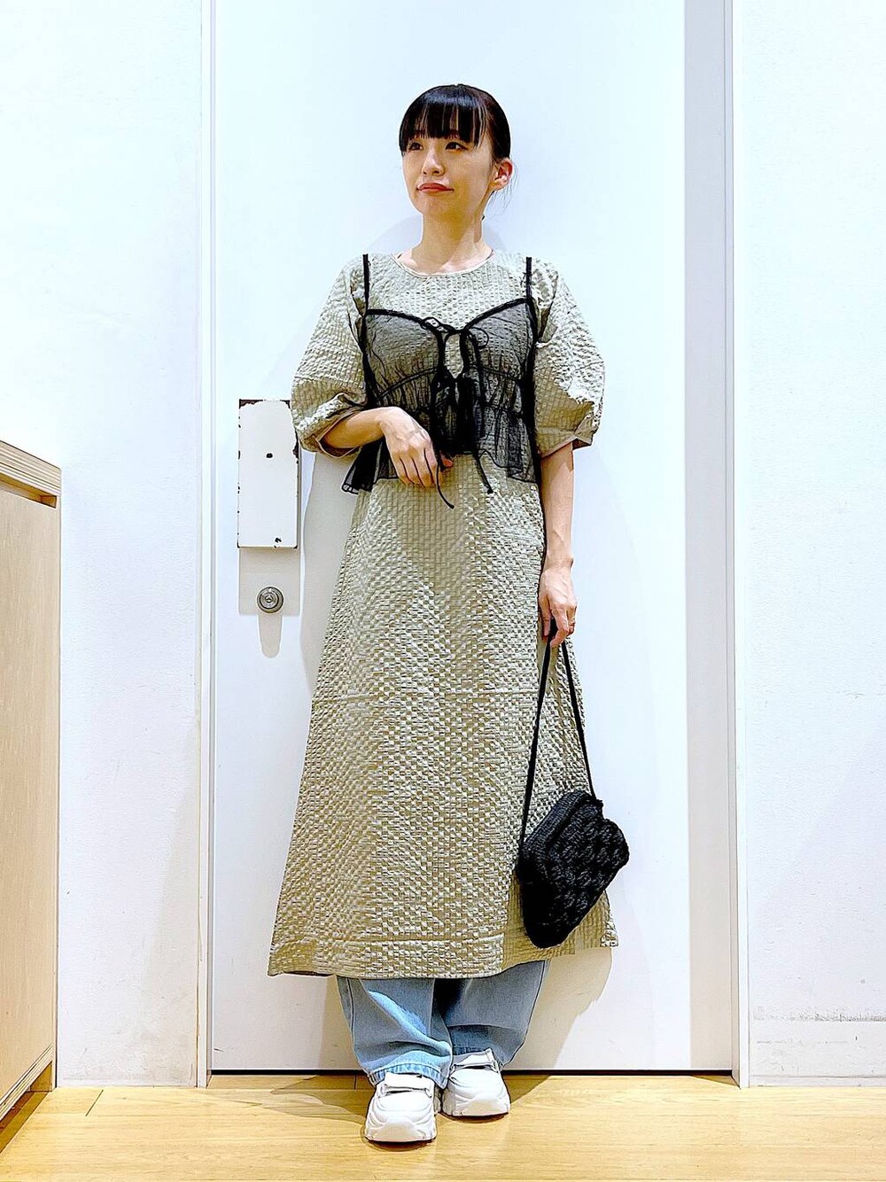 ホワイト系のスニーカー、ブルー系のデニムパンツ、ブラック系のショルダーバッグを着用したレディースの春コーディネートの1枚目の写真