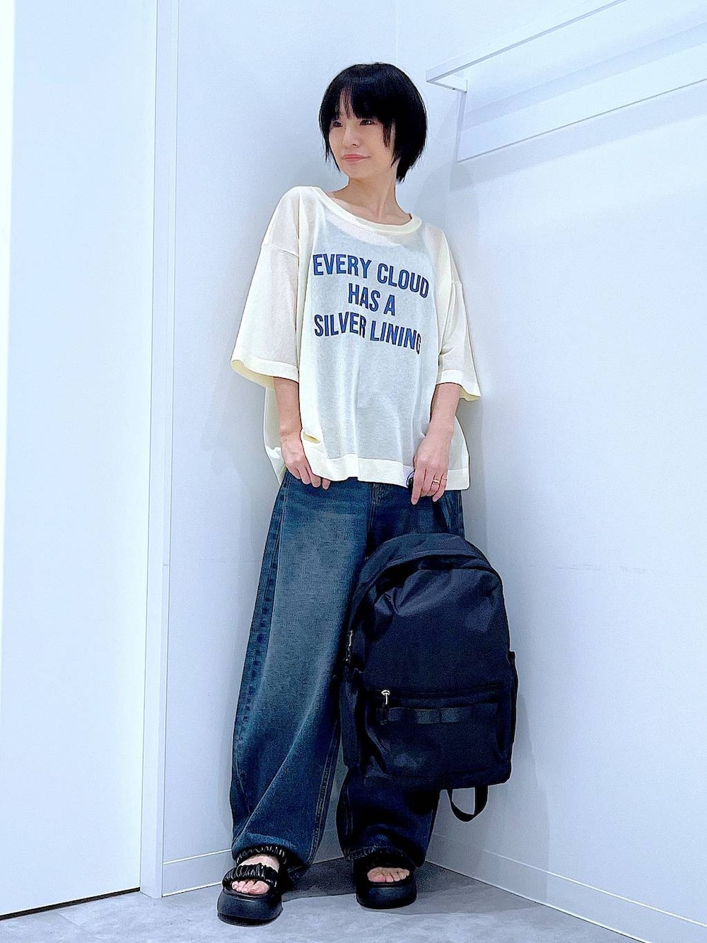 ブルー系のデニムパンツ、ブラック系のバックパック/リュック、ブラック系のサンダルを着用したレディースの夏コーディネートの1枚目の写真