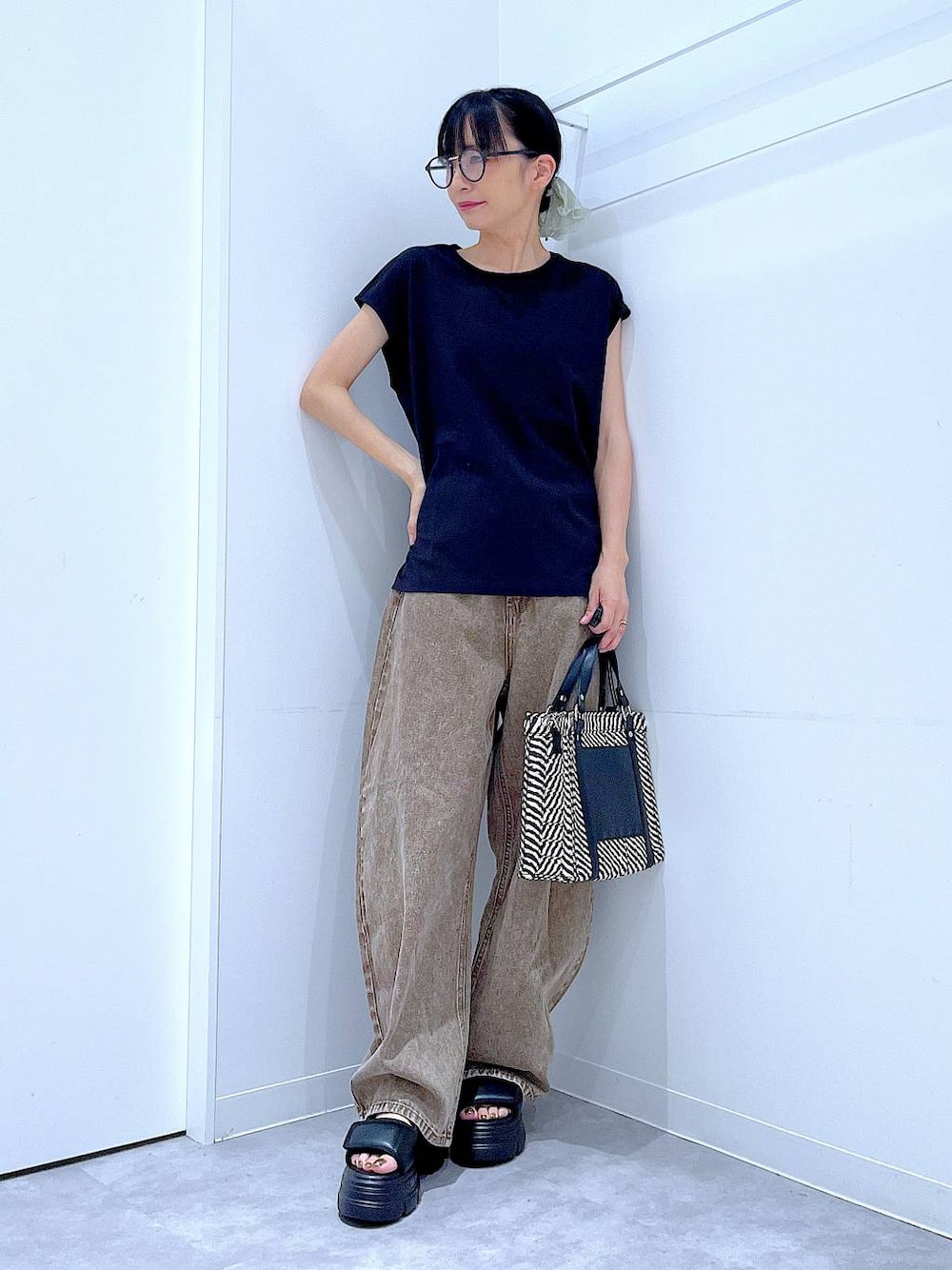 ブラウン系のデニムパンツ、その他のショルダーバッグ、ブラック系のサンダルを着用したレディースの夏コーディネートの1枚目の写真