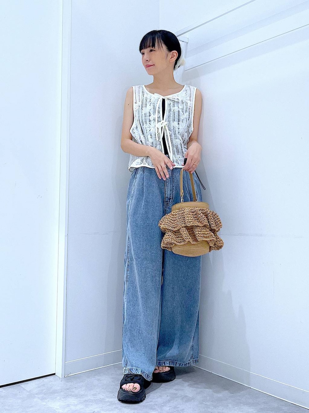 ベージュ系のショルダーバッグ、ブルー系のデニムパンツ、ベージュ系のベストを着用したレディースの夏コーディネートの1枚目の写真