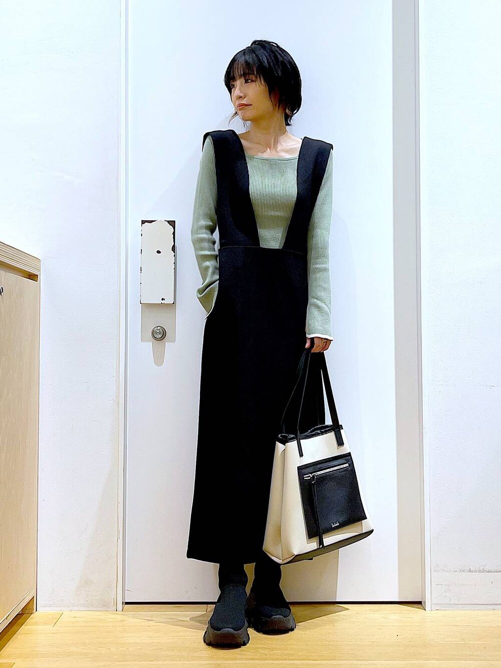 グリーン系のニット/セーター、ブラック系のブーツ、ブラック系のサロペット/オーバーオールを着用したレディースの冬コーディネートの1枚目の写真