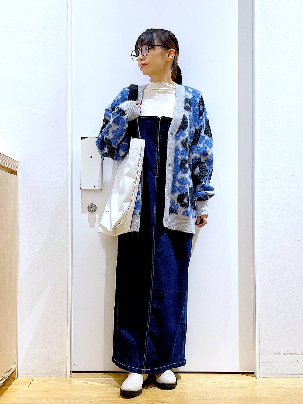 ブルー系のジャンパースカート、ホワイト系のTシャツ/カットソー、ベージュ系のブーツを着用したレディースの冬コーディネートの1枚目の写真