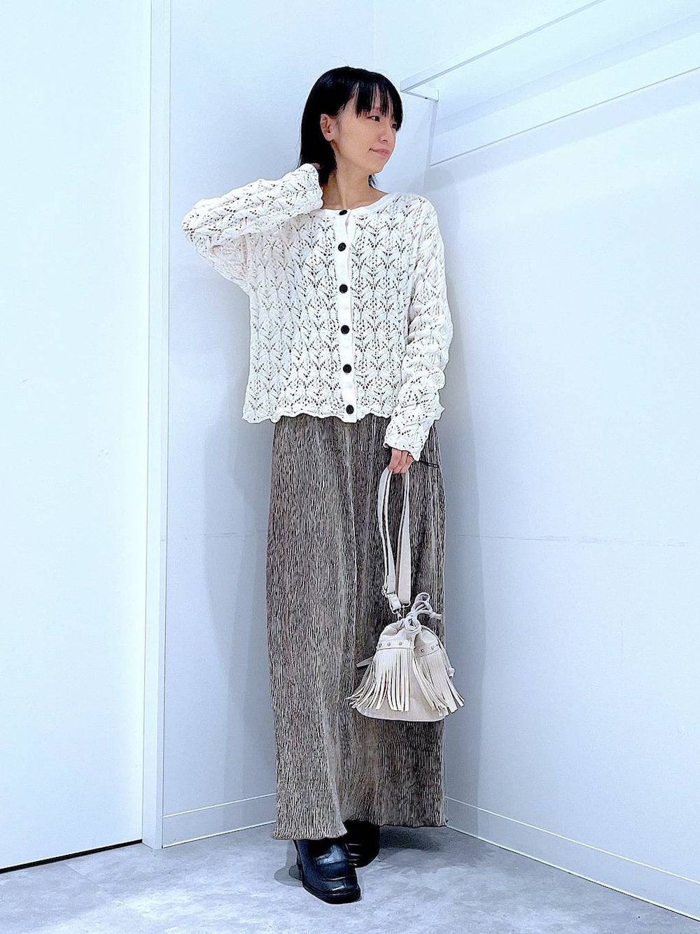 ブラック系のブーツ、ホワイト系のショルダーバッグ、ベージュ系のカーディガン/ボレロを着用したレディースの冬コーディネートの1枚目の写真