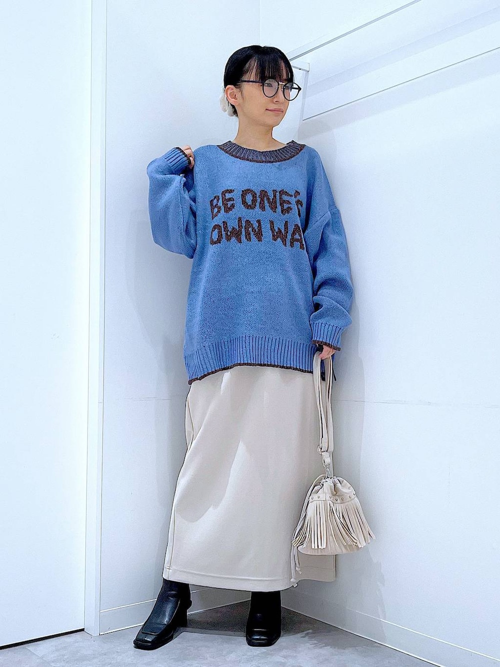 ベージュ系のスカート、ブラック系のブーツ、ホワイト系のショルダーバッグを着用したレディースの冬コーディネートの1枚目の写真