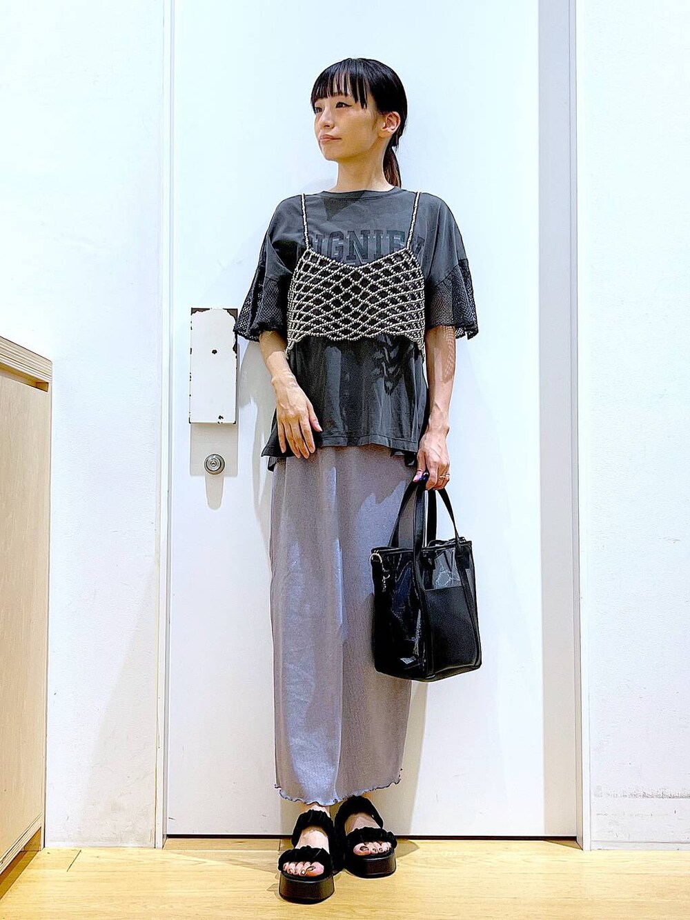 パープル系のスカート、ブラック系のサンダル、ブラック系のトートバッグを着用したレディースの夏コーディネートの1枚目の写真