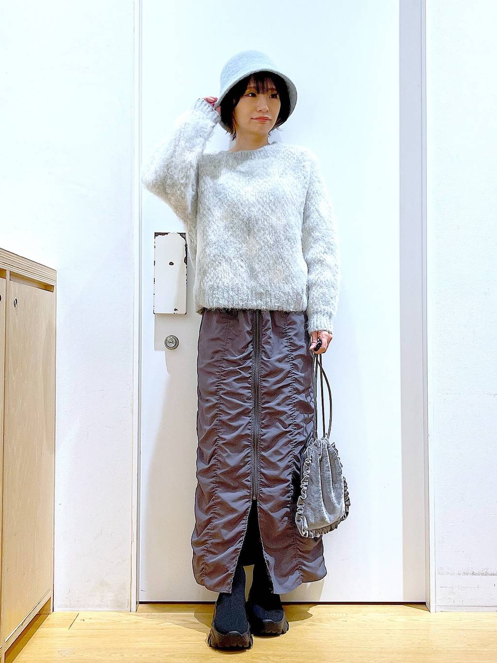 グレー系のショルダーバッグ、グレー系のスカート、ブラック系のブーツを着用したレディースの冬コーディネートの1枚目の写真