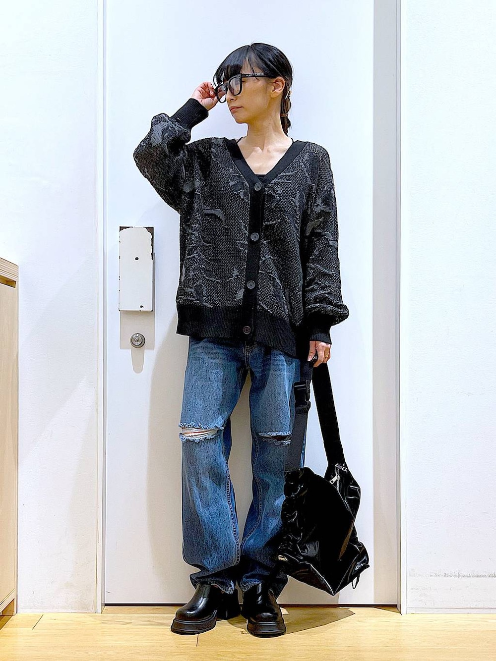 ブラック系のサンダル、ブラック系のカーディガン/ボレロ、ブルー系のデニムパンツを着用したレディースの春コーディネートの1枚目の写真