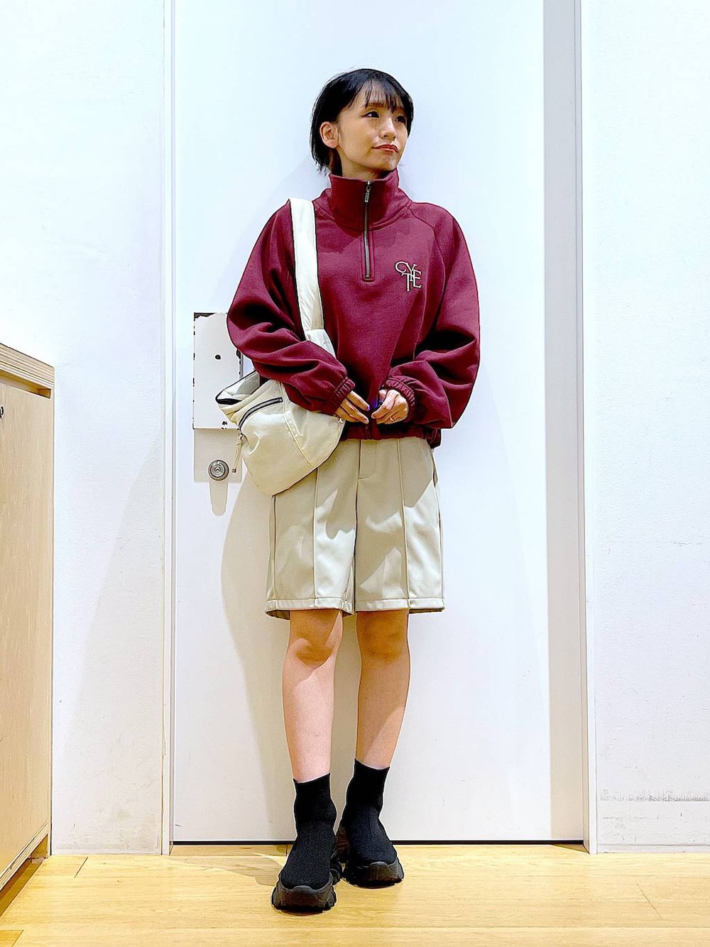 ホワイト系のショルダーバッグ、ブラック系のブーツ、レッド系のスウェットを着用したレディースの冬コーディネートの1枚目の写真