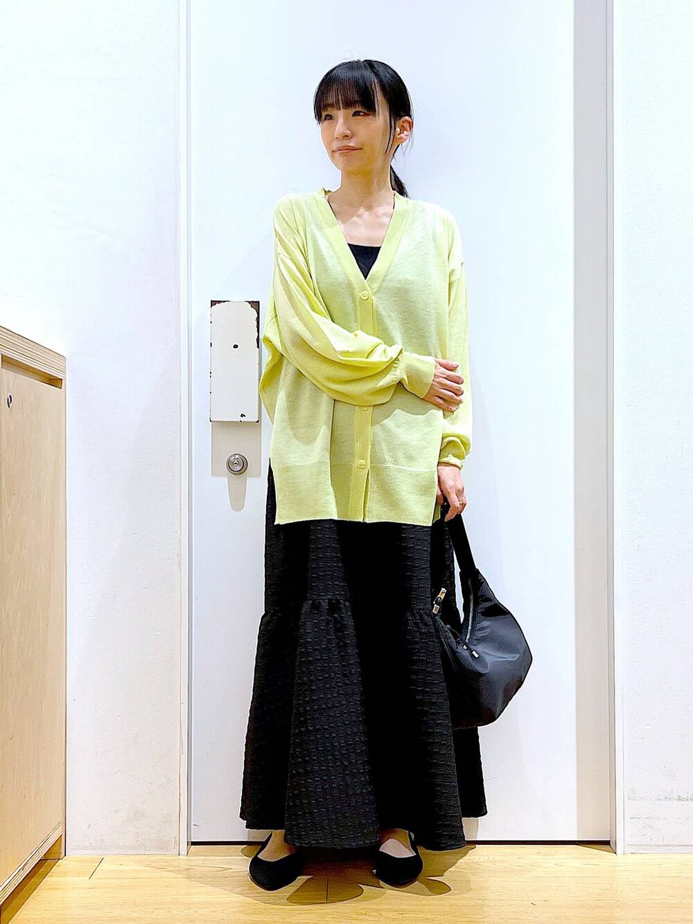 ブラック系のワンピース、グリーン系のカーディガン/ボレロ、ブラック系のショルダーバッグを着用したレディースの春コーディネートの1枚目の写真