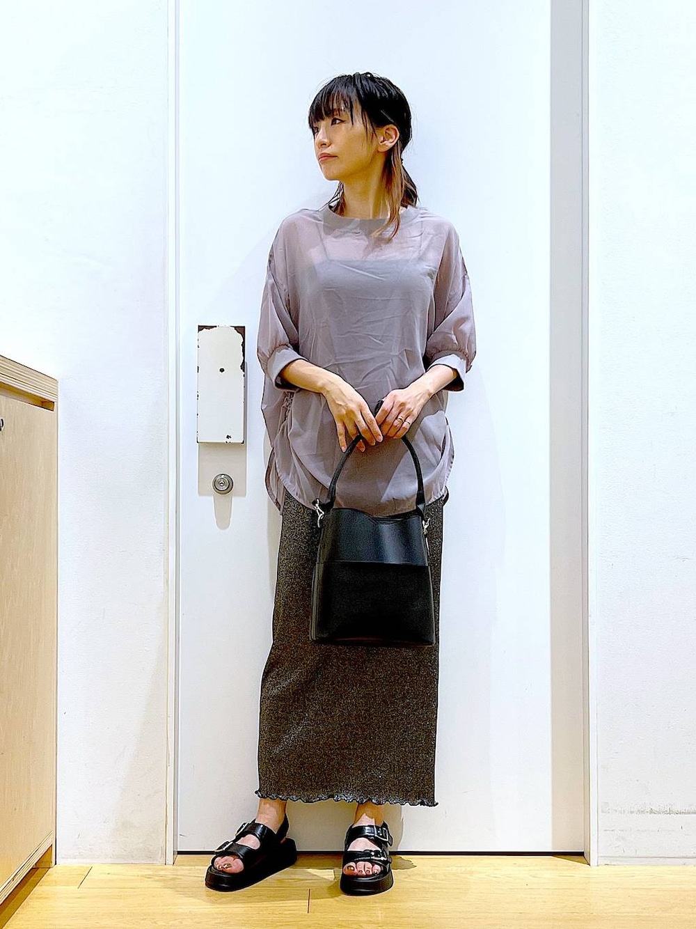 ブラック系のスカート、ブラック系のショルダーバッグ、ブラック系のサンダルを着用したレディースの夏コーディネートの1枚目の写真