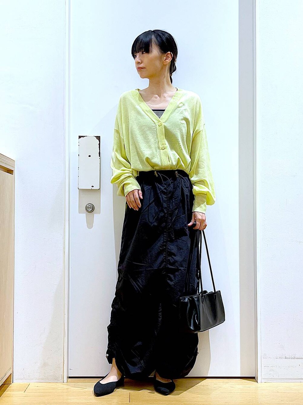 ホワイト系のキャミソール、グリーン系のカーディガン/ボレロ、ブラック系のトートバッグを着用したレディースの春コーディネートの1枚目の写真