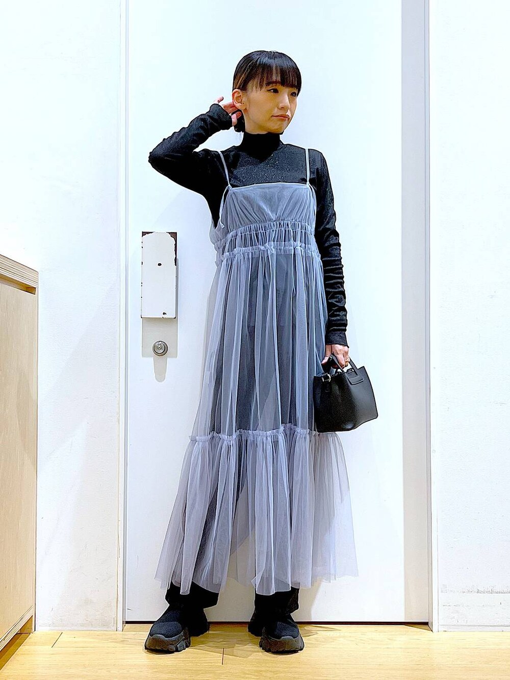 グレー系のデニムパンツ、ブルー系のワンピース、ブラック系のTシャツ/カットソーを着用したレディースの春コーディネートの1枚目の写真