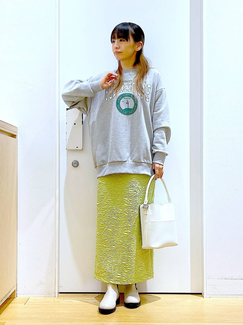 グリーン系のスカート、グレー系のスウェット、ホワイト系のショルダーバッグを着用したレディースの春コーディネートの1枚目の写真
