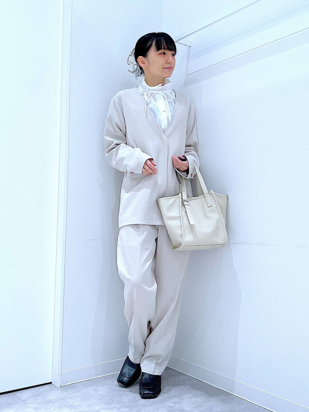 ブラック系のブーツ、ホワイト系のトートバッグ、ベージュ系のノーカラージャケットを着用したレディースの冬コーディネートの1枚目の写真