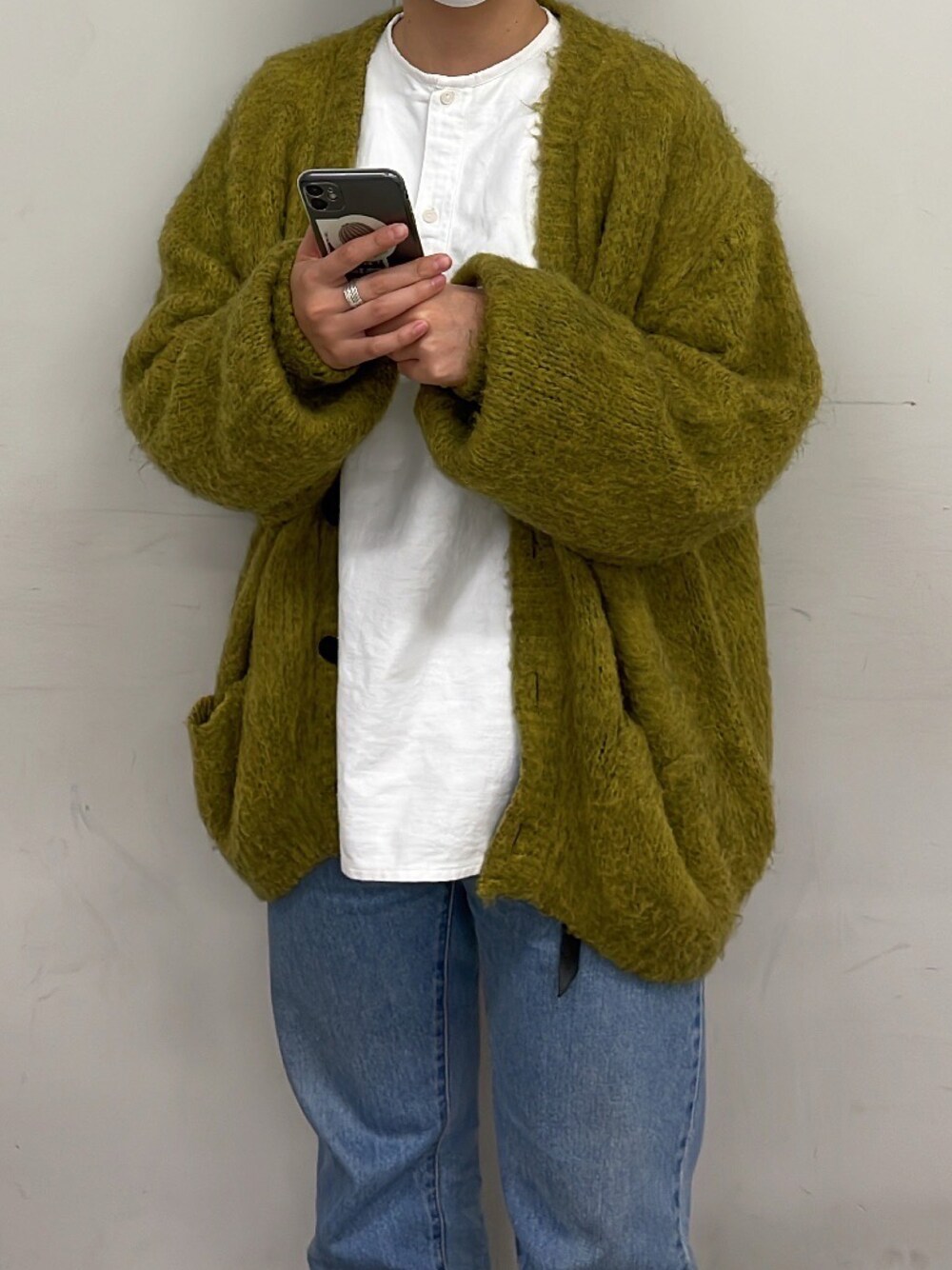 イエロー系のカーディガン/ボレロ、ホワイト系のシャツ/ブラウス、ブルー系のデニムパンツを着用したレディースの冬コーディネートの1枚目の写真