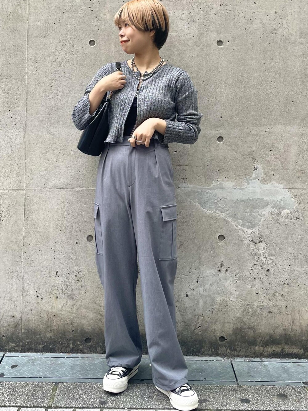 ブラック系のスニーカー、グレー系のカーゴパンツ、ブラック系のニット/セーターを着用したレディースの冬コーディネートの1枚目の写真