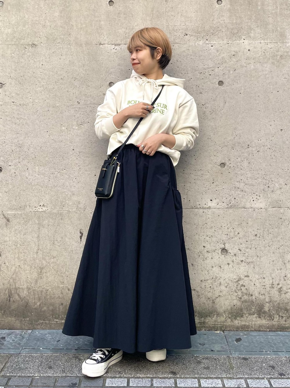 ブラック系のスニーカー、ブラック系のスカート、ブラック系のショルダーバッグを着用したレディースの春コーディネートの1枚目の写真