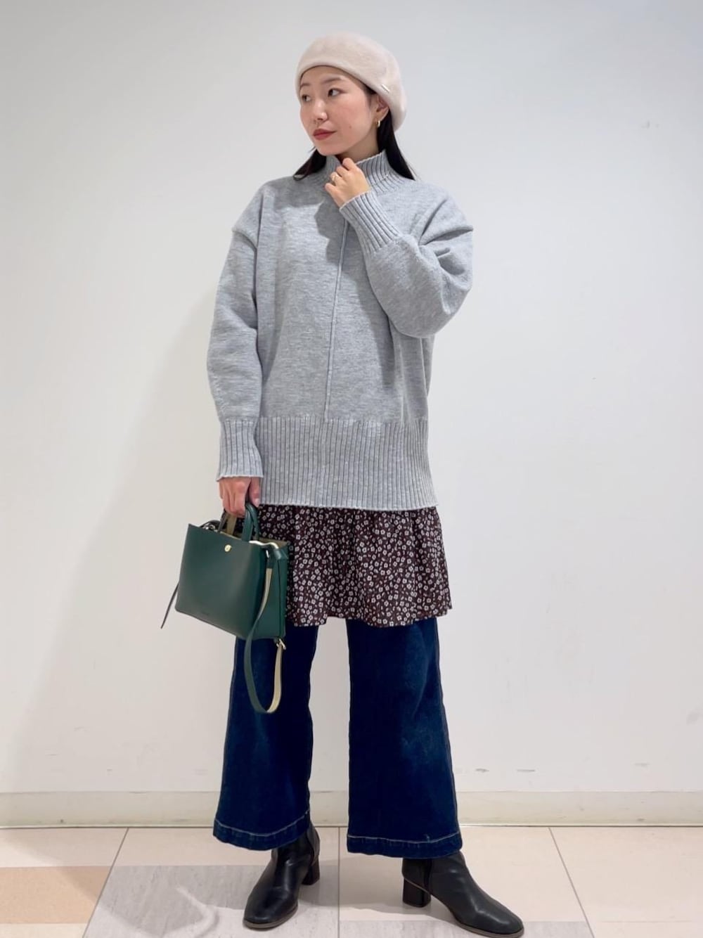 ブルー系のデニムパンツ、グレー系のニット/セーター、ブラウン系のワンピースを着用したレディースの冬コーディネートの1枚目の写真