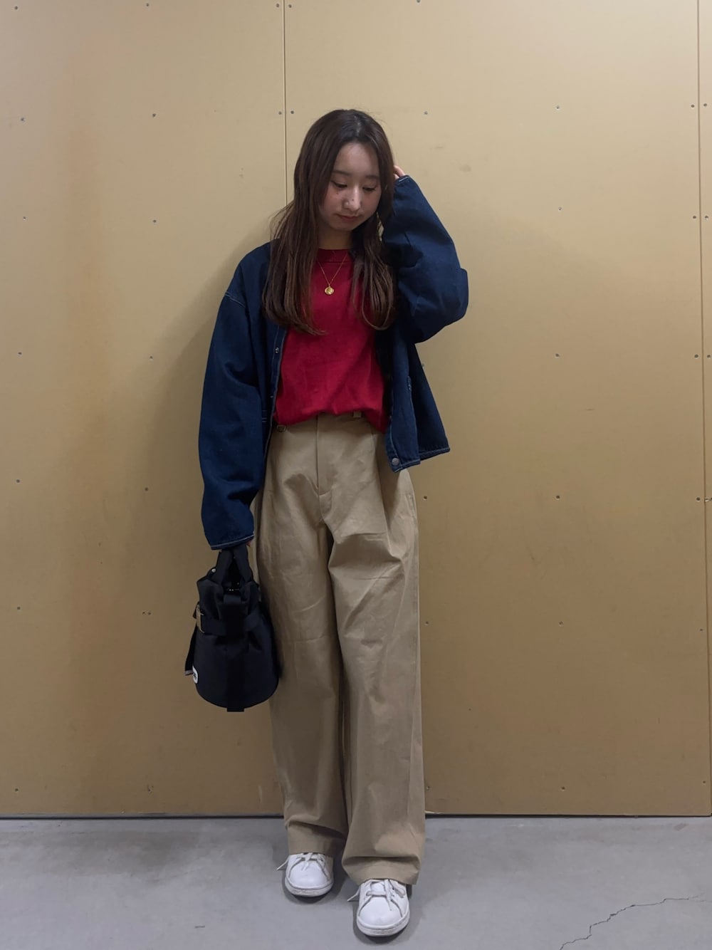 レッド系のニット/セーター、ブルー系のデニムジャケット、ベージュ系のチノパンツを着用したレディースの冬コーディネートの1枚目の写真