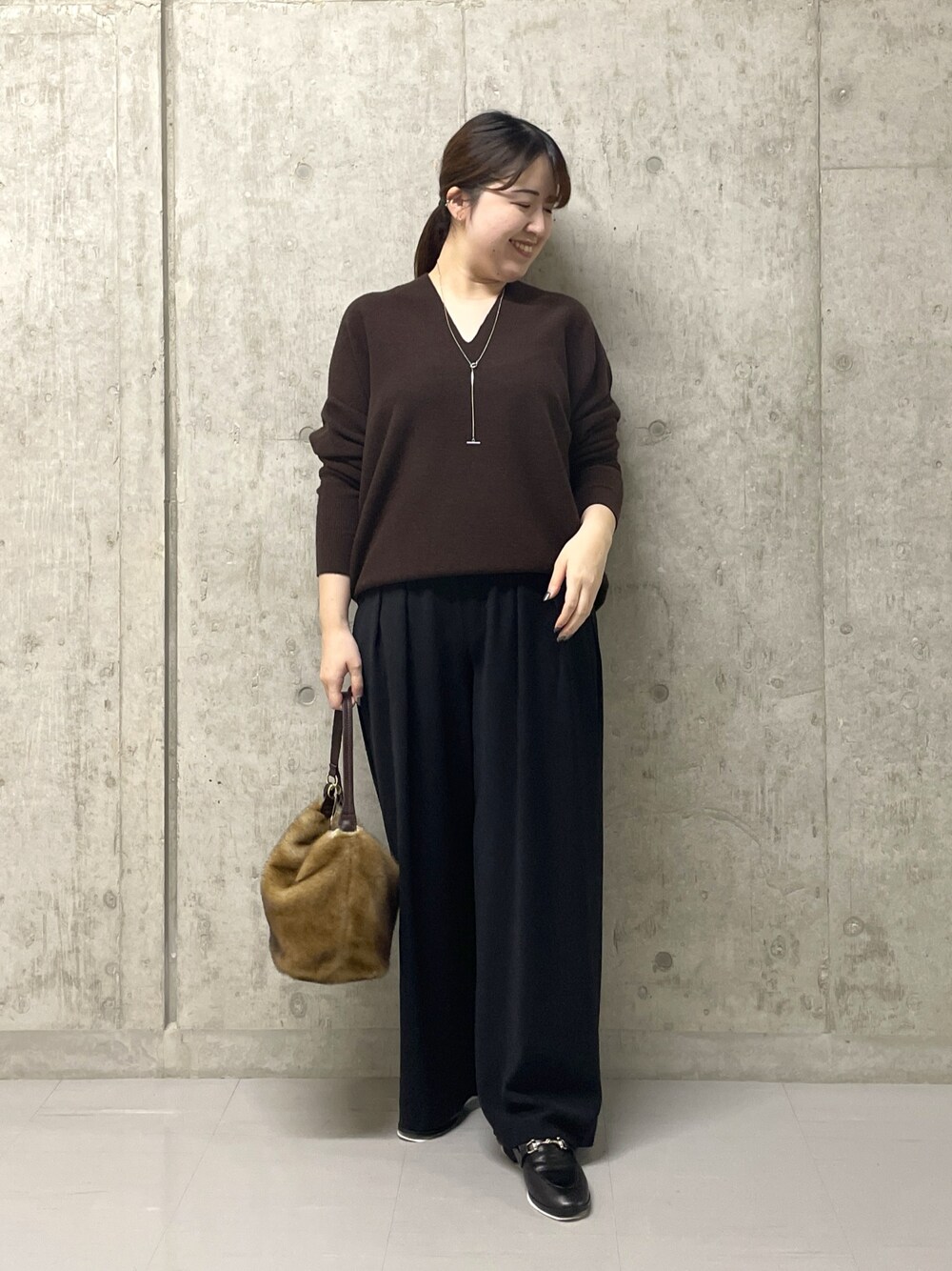 ブラウン系のニット/セーター、ブラック系のスラックス、イエロー系のハンドバッグを着用したレディースの秋コーディネートの1枚目の写真