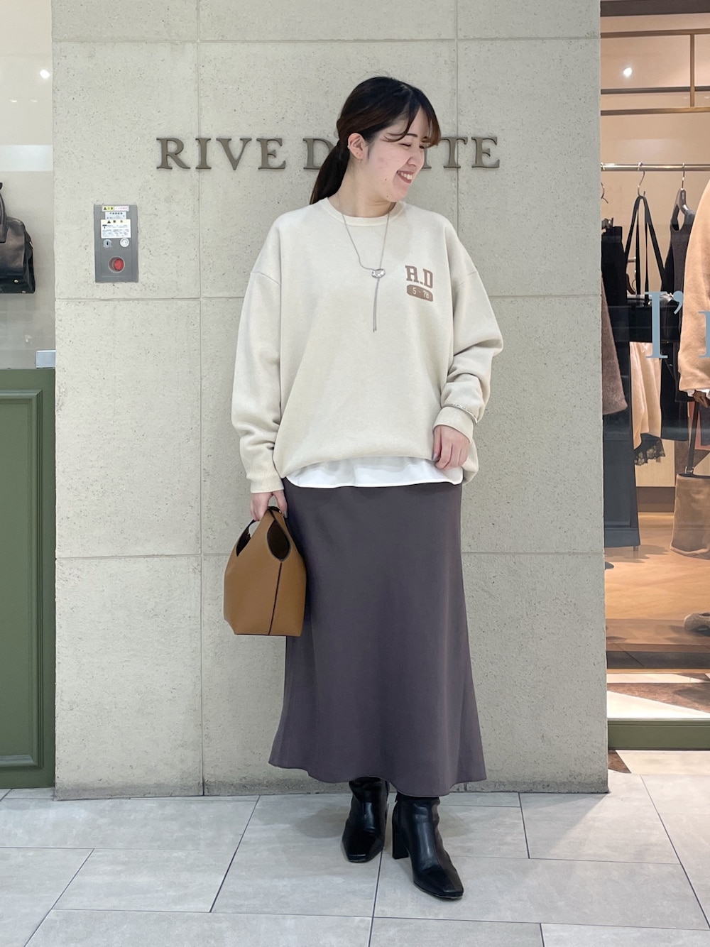 ホワイト系のニット/セーター、ホワイト系のTシャツ/カットソー、ブラウン系のスカートを着用したレディースの秋コーディネートの1枚目の写真