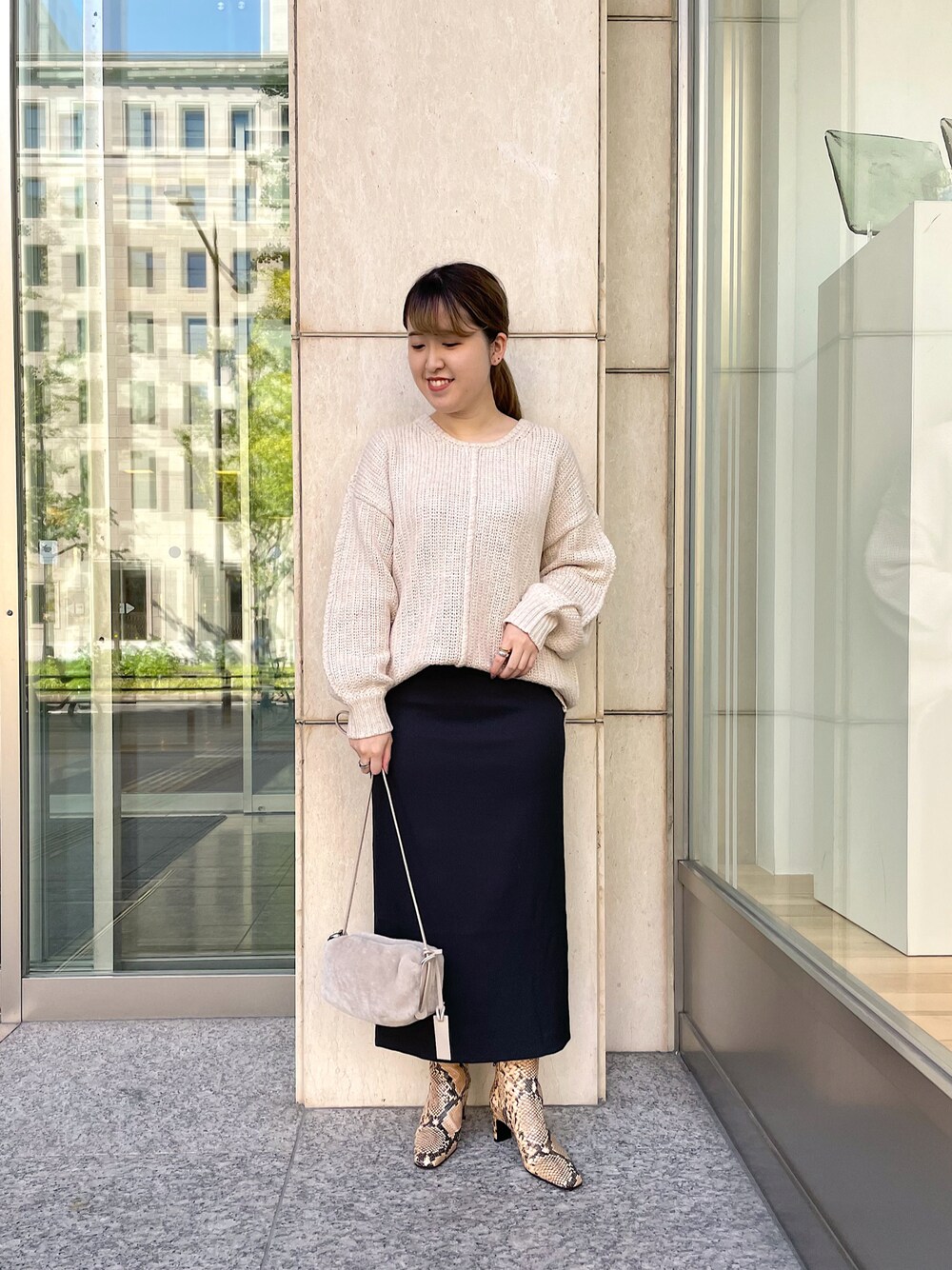 ベージュ系のニット/セーター、ブラック系のスカート、ベージュ系のショルダーバッグを着用したレディースの秋コーディネートの1枚目の写真
