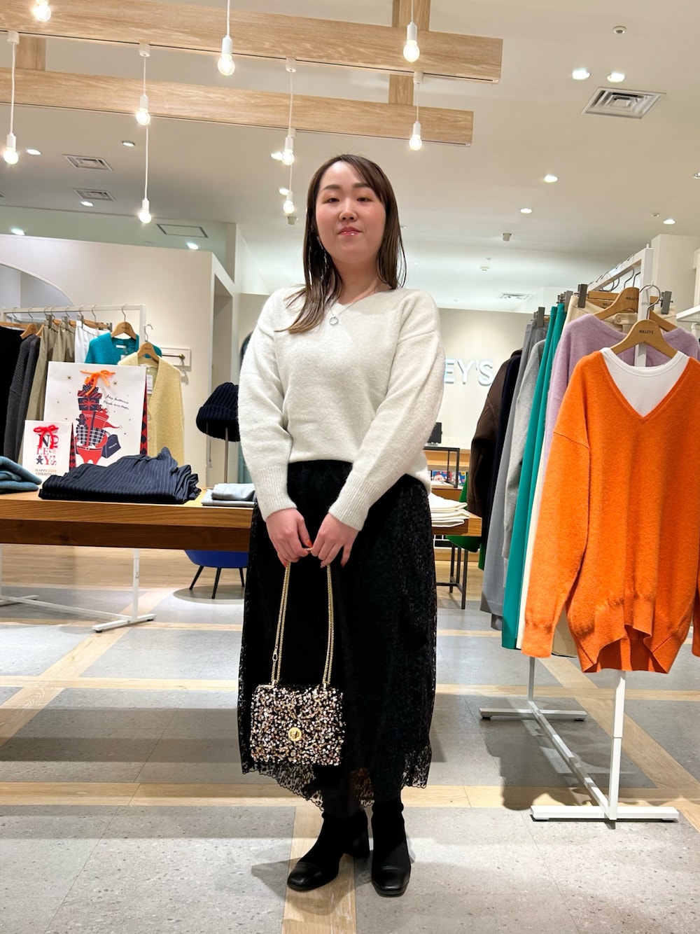 ホワイト系のニット/セーター、ブラック系のスカート、その他のショルダーバッグを着用したレディースの冬コーディネートの1枚目の写真