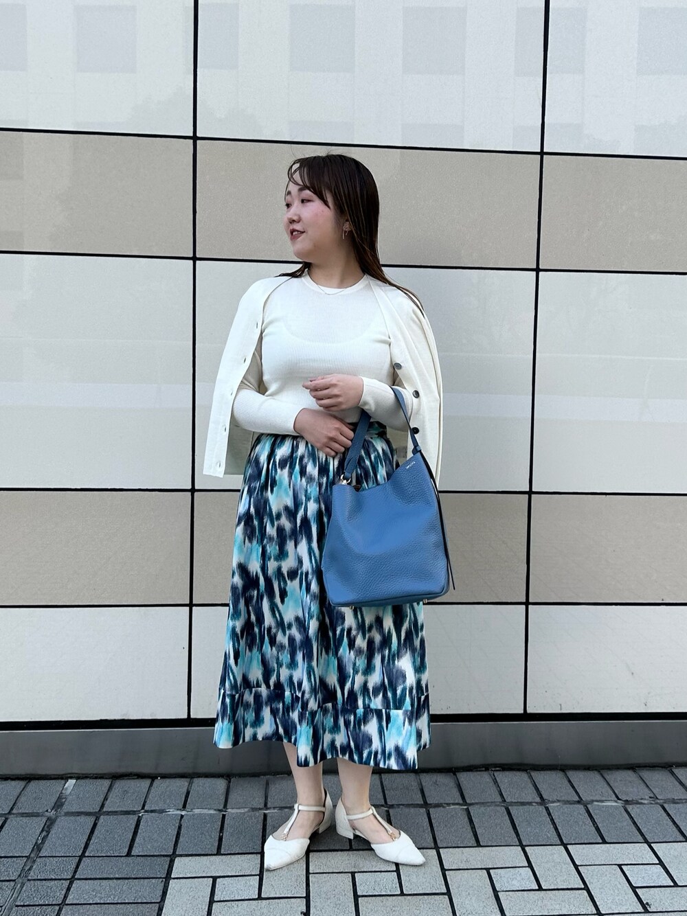 ホワイト系のカーディガン/ボレロ、ホワイト系のニット/セーター、ブルー系のスカートを着用したレディースの秋コーディネートの1枚目の写真