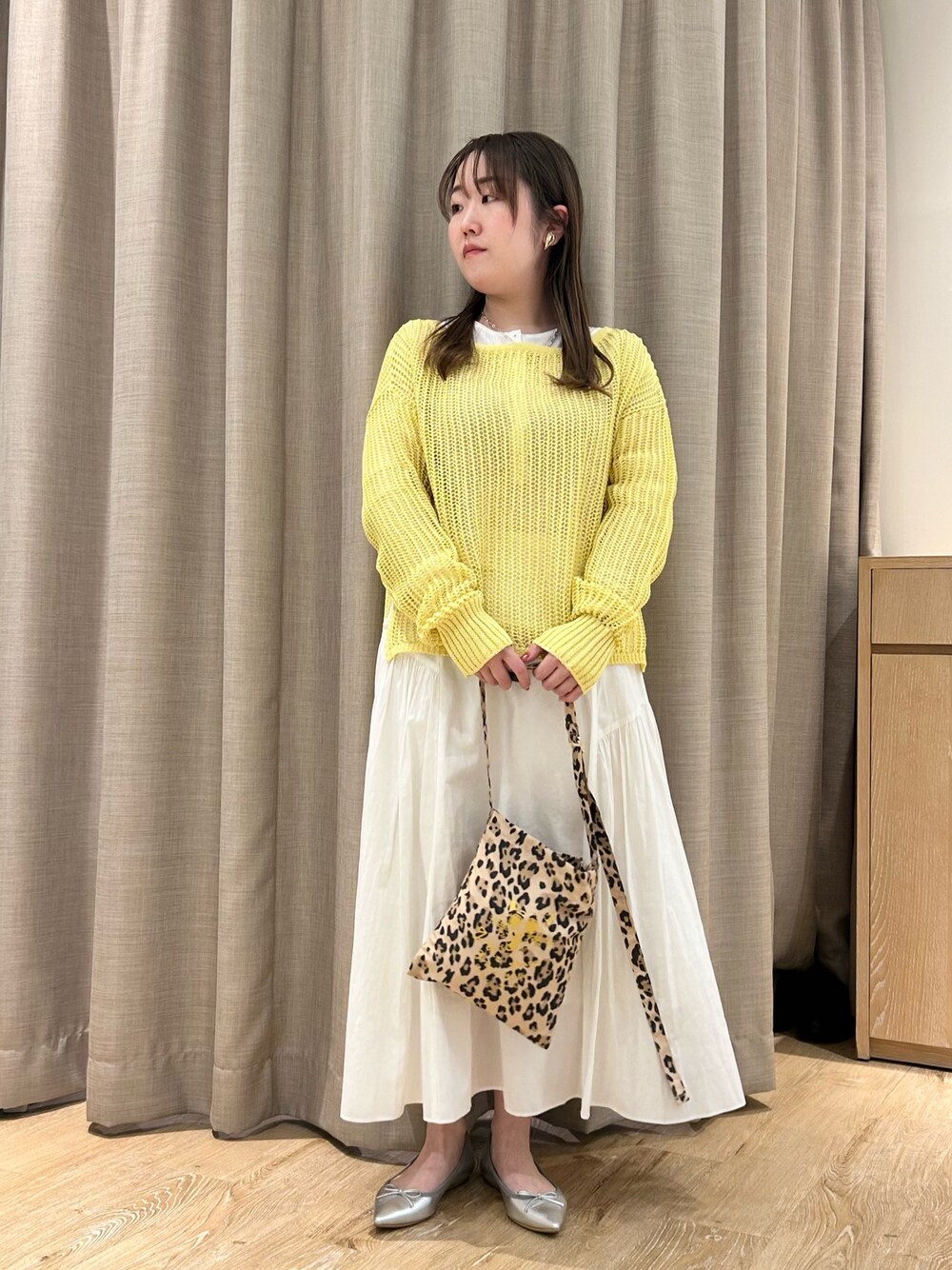 イエロー系のニット/セーター、ホワイト系のTシャツ/カットソー、ホワイト系のスカートを着用したレディースの春コーディネートの1枚目の写真