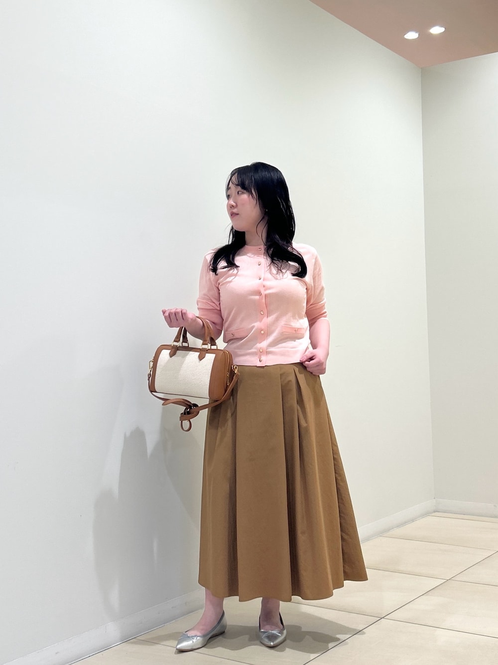 ピンク系のカーディガン/ボレロ、イエロー系のスカート、ブラウン系のボストンバッグを着用したレディースの夏コーディネートの1枚目の写真