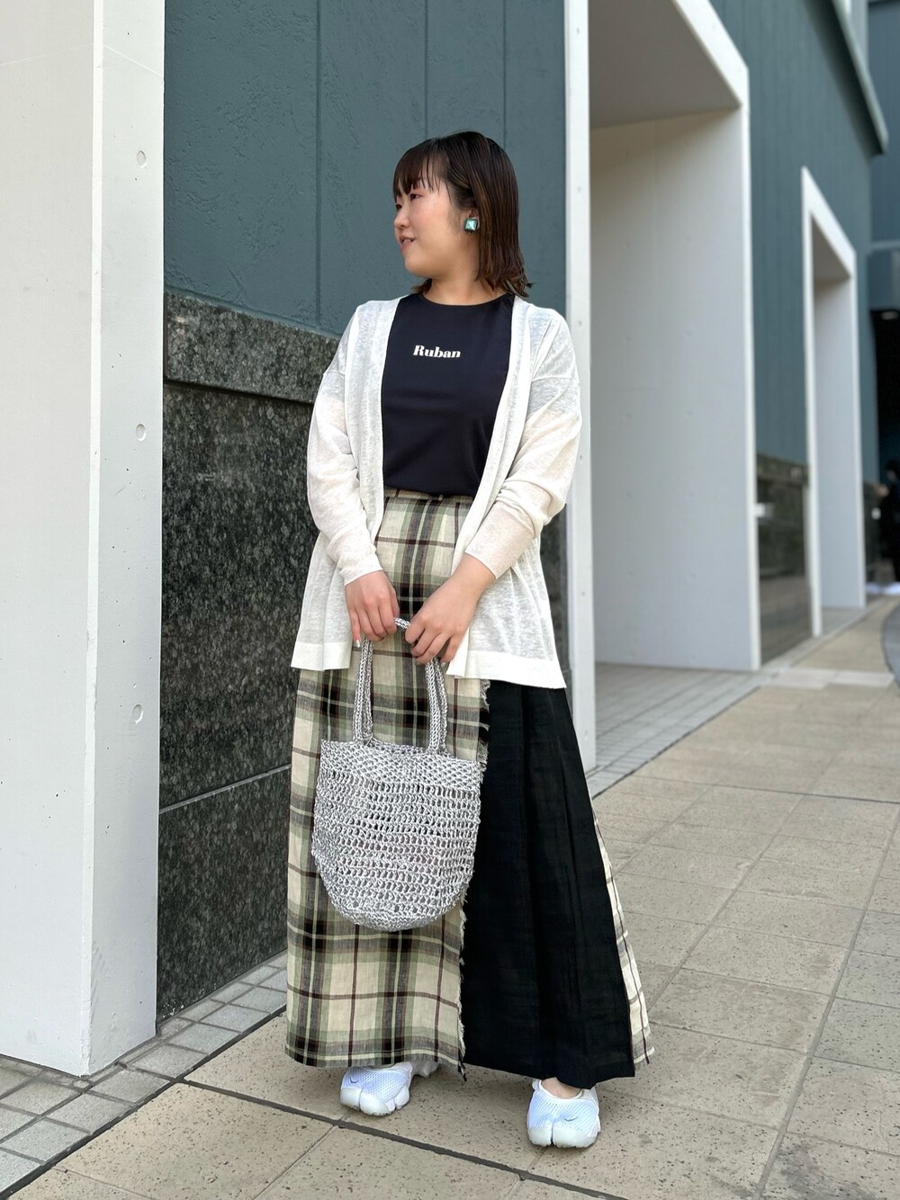ホワイト系のカーディガン/ボレロ、ブラック系のスカート、シルバー系のバックパック/リュックを着用したレディースの春コーディネートの1枚目の写真