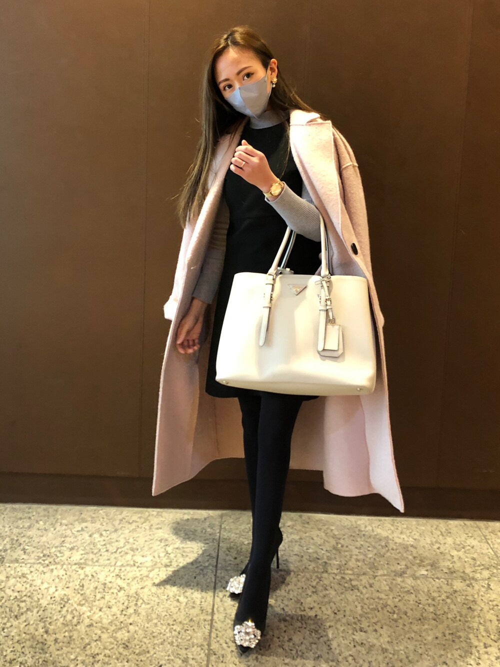 ホワイト系のトートバッグ、ピンク系のノーカラーコートを着用したレディースの冬コーディネートの1枚目の写真