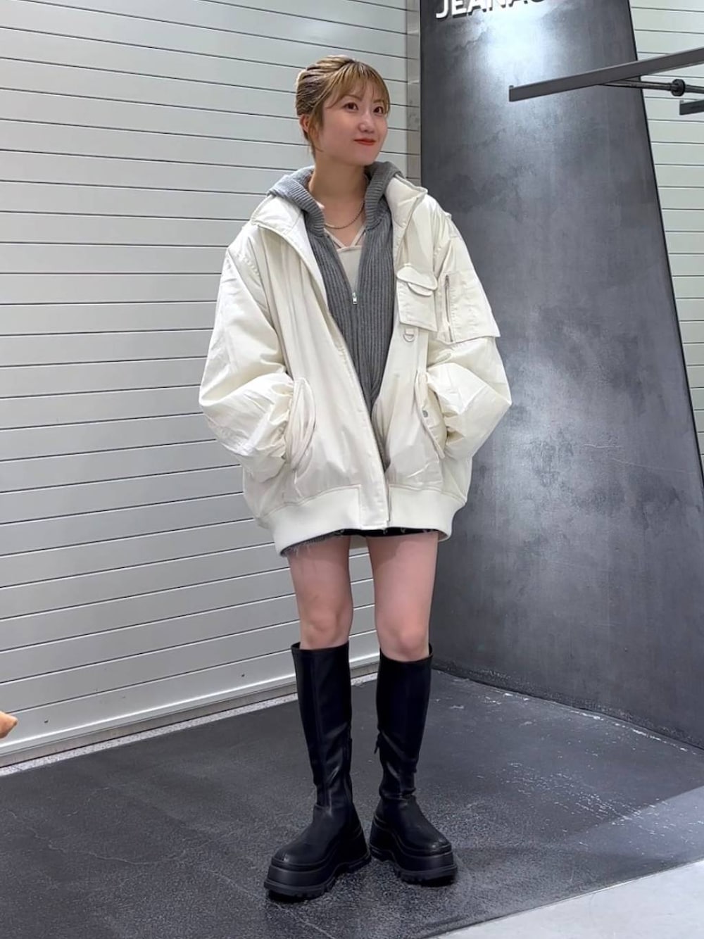 ホワイト系のブルゾン、ブラック系のブーツ、ホワイト系のタンクトップを着用したレディースの秋コーディネートの1枚目の写真