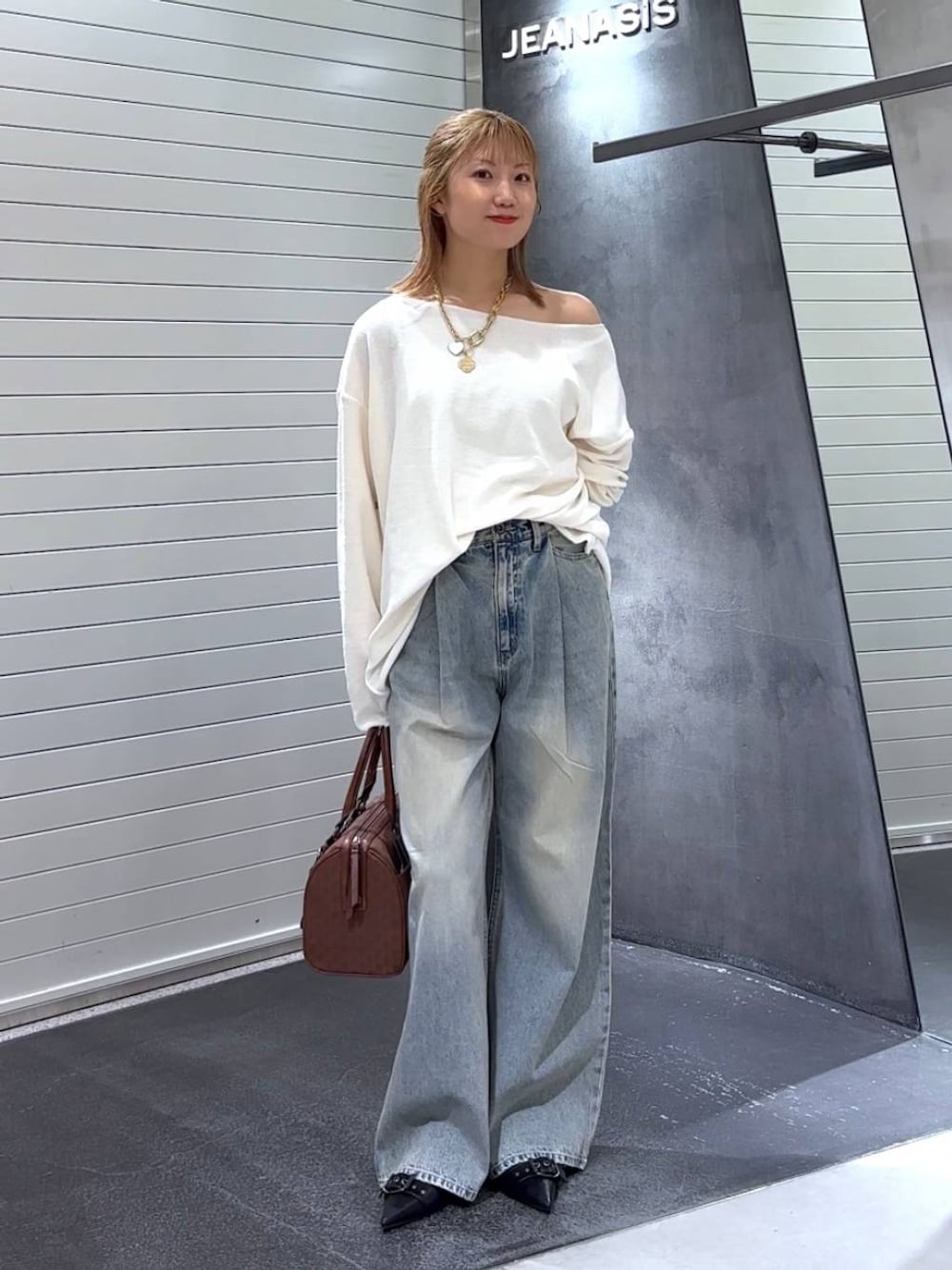 ブルー系のデニムパンツ、ブラック系のパンプス、レッド系のボストンバッグを着用したレディースの秋コーディネートの1枚目の写真