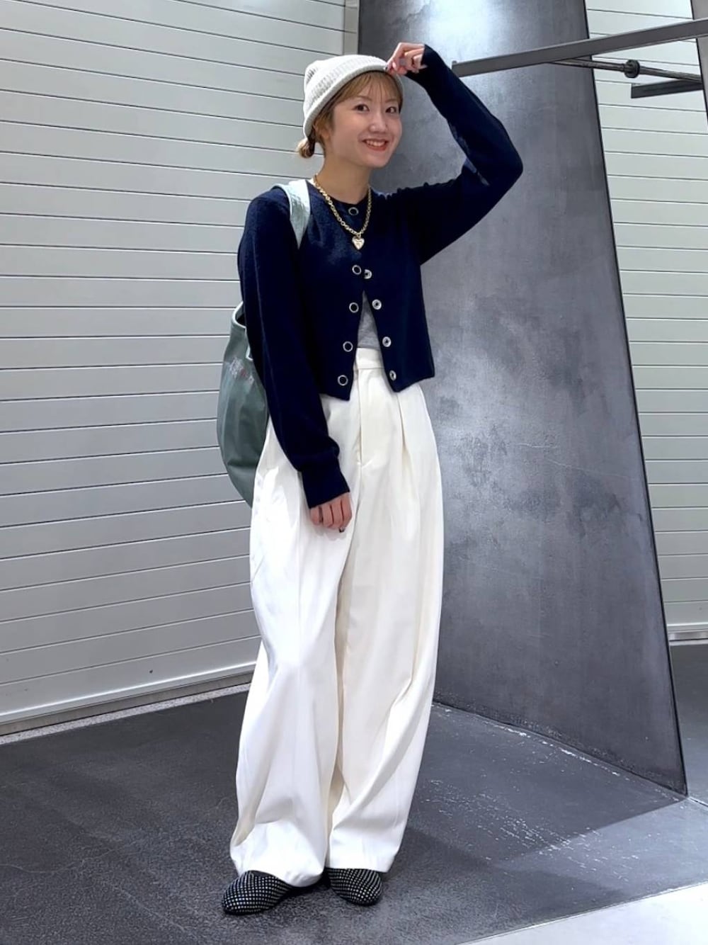 グリーン系のトートバッグ、ブラック系のパンプス、ホワイト系のスラックスを着用したレディースの秋コーディネートの1枚目の写真