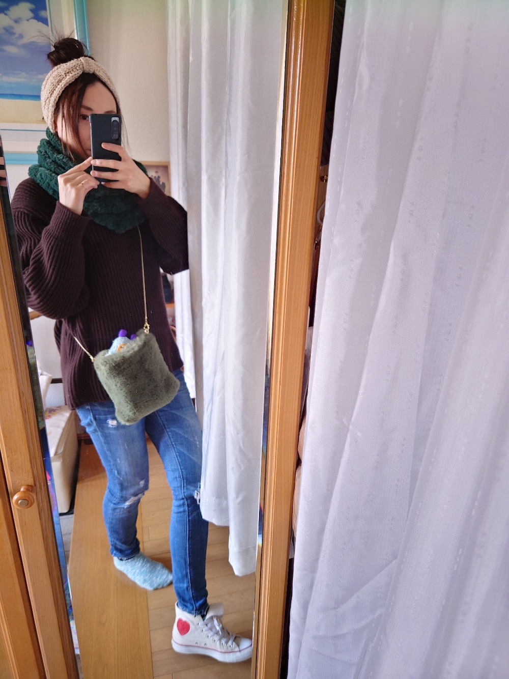 ブルー系のデニムパンツ、ブラウン系のニット/セーター、ホワイト系のヘアバンドを着用したレディースの冬コーディネートの4枚目の写真