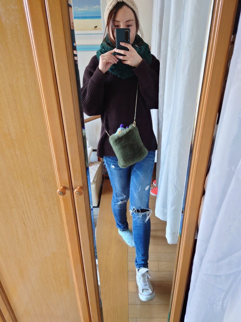 ブルー系のデニムパンツ、ブラウン系のニット/セーター、ホワイト系のヘアバンドを着用したレディースの冬コーディネートの2枚目の写真