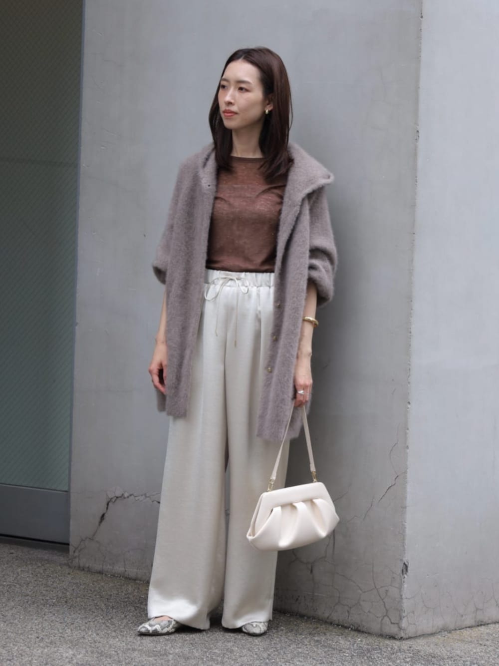 ベージュ系のその他アウター、グレー系のニット/セーター、ホワイト系のクラッチバッグを着用したレディースの秋コーディネートの1枚目の写真