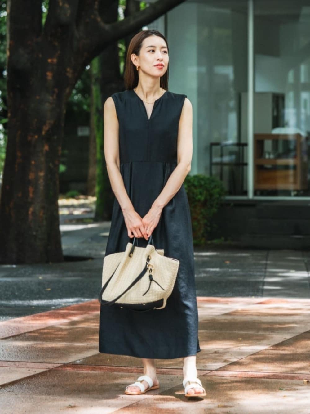 ブラック系のワンピース、ホワイト系のサンダル、ベージュ系のかごバッグを着用したレディースの夏コーディネートの1枚目の写真
