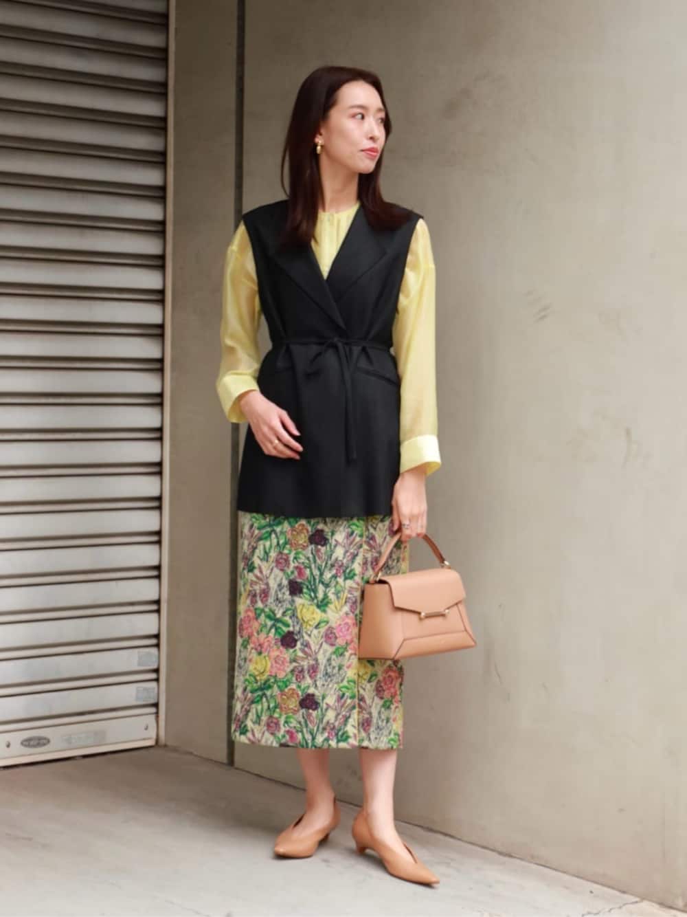 イエロー系のシャツ/ブラウス、ブラック系のベスト、グリーン系のスカートを着用したレディースの春コーディネートの1枚目の写真